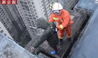 Người lính cứu hỏa tiếp cận và giữ chặt cậu bé đứng ngoài rìa của tòa nhà 33 tầng