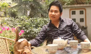 Trọng Tấn bên cạnh một trong ba con mèo đang được anh nuôi ở nhà. Ảnh: Quang Đức.
