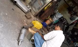 Một thợ đang cắt, độ lại pô mô tô tại tiệm ông H.