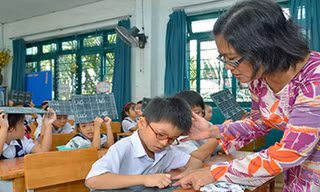Cô giáo uốn nắn cho học trò từng nét chữ, nết người. Ảnh: Tấn Thạnh/Người Lao Động.