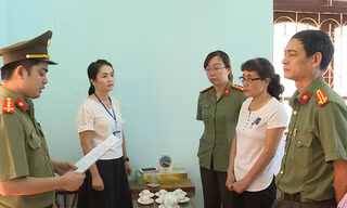 Bị can Nguyễn Thị Hồng Nga (áo trắng bên phải) nghe tống đạt quyết định khởi tố.
