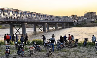 Người dân và người nhà nạn nhân chờ đợi trên bờ sông Tigris sau vụ tai nạn chìm phà. Ảnh: AP.