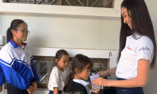 Á hậu Nguyễn Thị Thúy An rót nước cho các trẻ em uống nước tại chương trình Ký túc xá 115, tại xã Ea Dah, huyện Krông Năng, tỉnh Đắk Lắk.