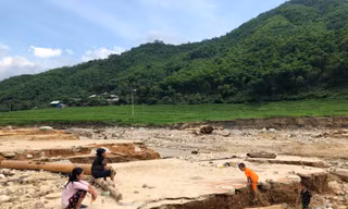 Cụ Nít cùng người thân ngồi bên nền nhà cũ bị lũ cuốn trôi, gọi tên các con đang mất tích. Ảnh: Hoàng Lam