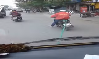 Xe máy kéo ôtô hết xăng đi trên phố Hà Nội