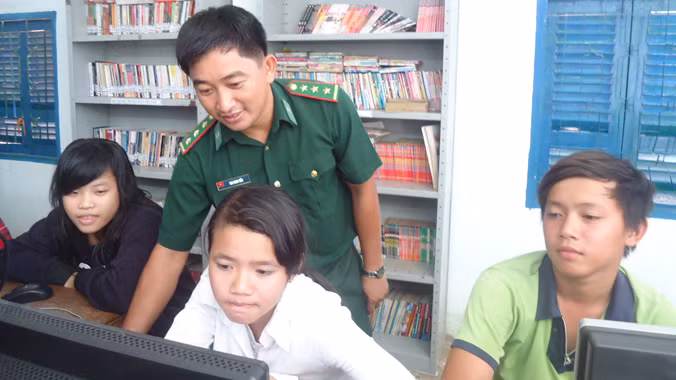 Thượng úy Bao Minh Tiến hướng dẫn các em tham gia “Lớp tin học cộng đồng Thiềng Liềng”.