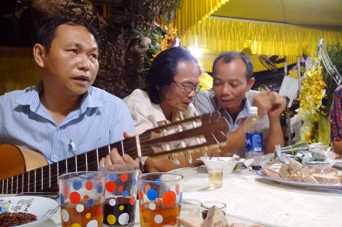 Tác giả Bùi Long ôm đàn trong đám tang thi sĩ Trần Vàng Sao. Ảnh: Trần Tuấn.