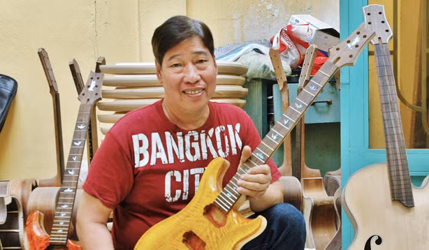 Nghệ nhân Ngọc Thức bên cây đàn ghita điện mà anh đang hoàn thiện. Ảnh: Trần Nguyễn Anh