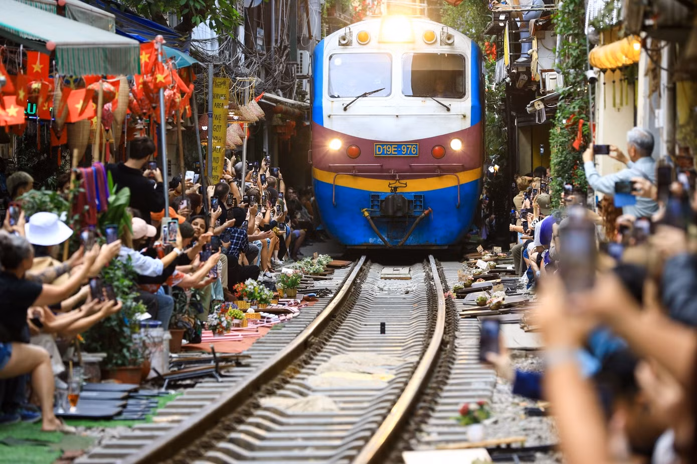 Du khách ngồi sát đường ray, đồng loạt quay phim, chụp ảnh khi đoàn tàu đi qua. Ảnh: Trần Hiền.