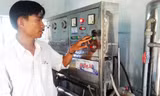 Anh Trần Hữu Tịnh điều khiển hệ thống sản xuất nước uống đóng chai Sức sống mới. Ảnh: Nguyễn Thành.