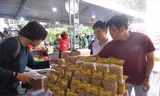 Chàng trai trẻ Tô Nhựt Điền (bên phải) giới thiệu bánh tráng kẹo cho khách hàng Ảnh: U.P 