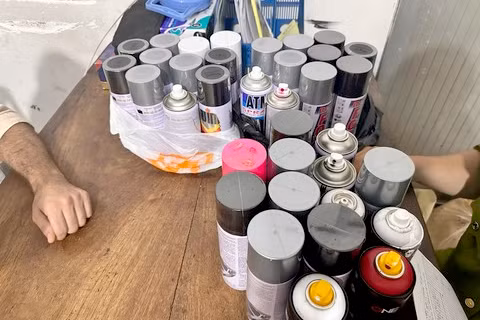 Các bình phun sơn được công an thu giữ.