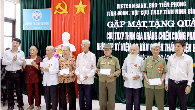 Nhà báo Trần Thanh Lâm (ngoài cùng bên phải), ông Đinh Mạnh Tuân, Phó giám đốc Ngân hàng Vietcombank chi nhánh Ninh Bình (ngoài cùng bên trái) trao quà cho cựu TNXP