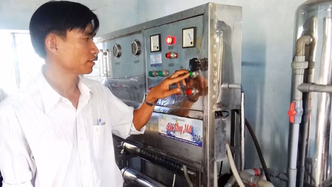 Anh Trần Hữu Tịnh điều khiển hệ thống sản xuất nước uống đóng chai Sức sống mới. Ảnh: Nguyễn Thành.