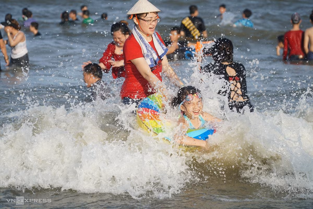 Cô bé được mẹ kéo phao vui đùa với sóng.
