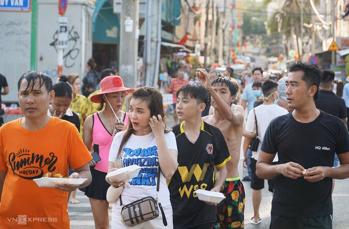 Một nhóm khách không đeo khẩu trang, xuất phát từ con hẻm có nhiều khách sạn, nhà nghỉ băng qua đường Thùy Vân để xuống bãi biển.