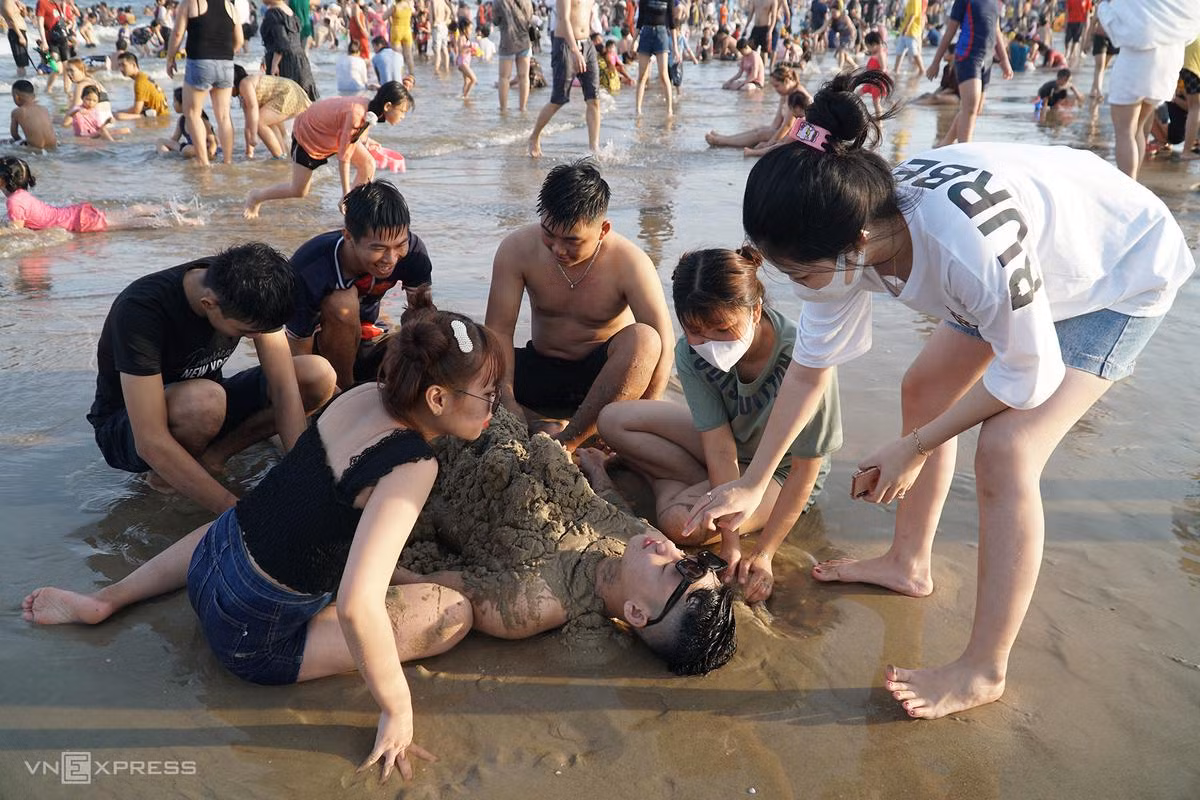 Nhóm khách đến từ TP HCM đắp cát lên người. "Mùa này nóng nực nên chúng tôi chọn Vũng Tàu để tắm thỏa thích. Giá dịch vụ những ngày này tăng nhưng ở mức chấp nhận được", anh Hoài đến từ TP Thủ Đức nói.