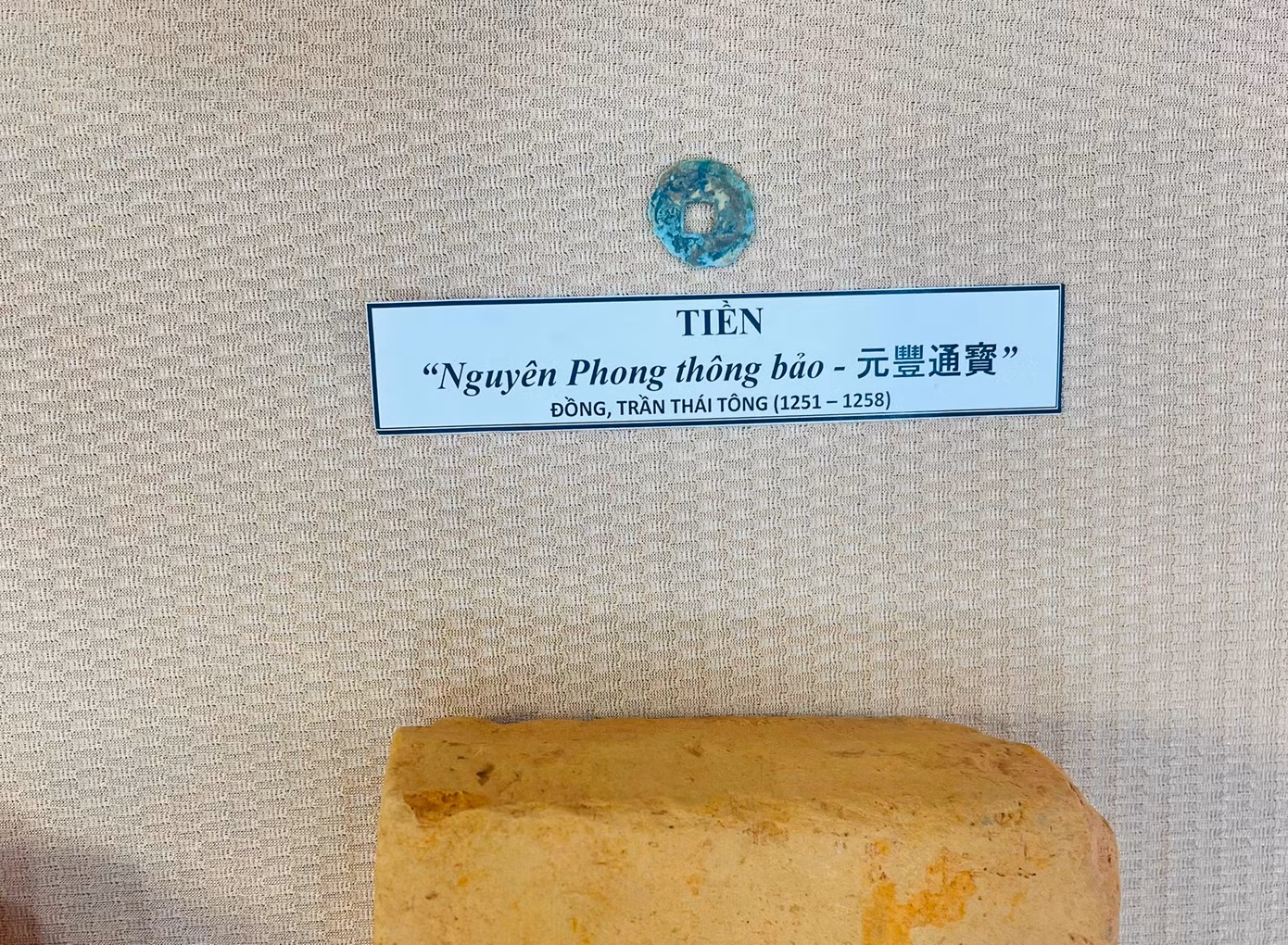 Đầu phù điêu Phật và tiền đồng được tìm thấy tại khu di tích.