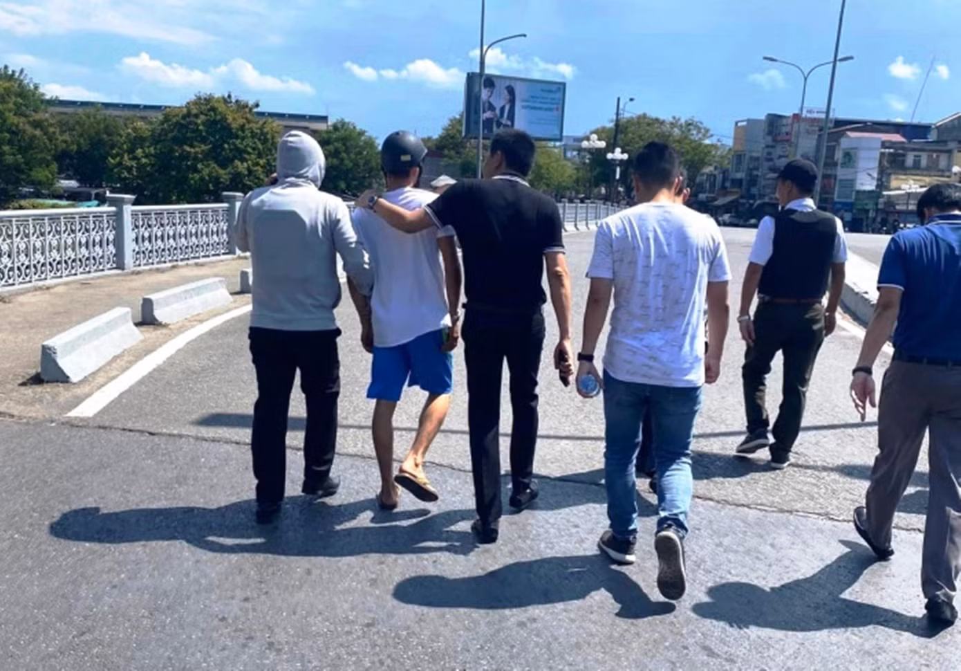 Dẫn giải nghi phạm cướp tiệm vàng (áo trắng, quần cộc màu xanh) về trụ sở công an