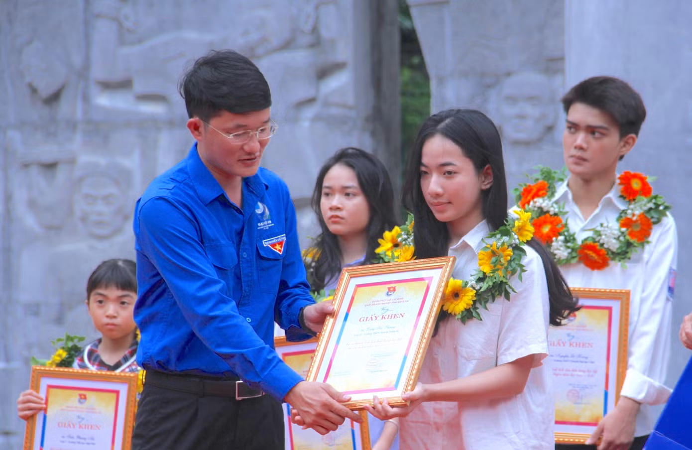 Ông Trần Quang Hòa và anh Trần Linh - Phó Bí thư Tỉnh Đoàn Nghệ An trao tặng Giấy khen, hoa tuyên dương các em học sinh tiêu biểu.