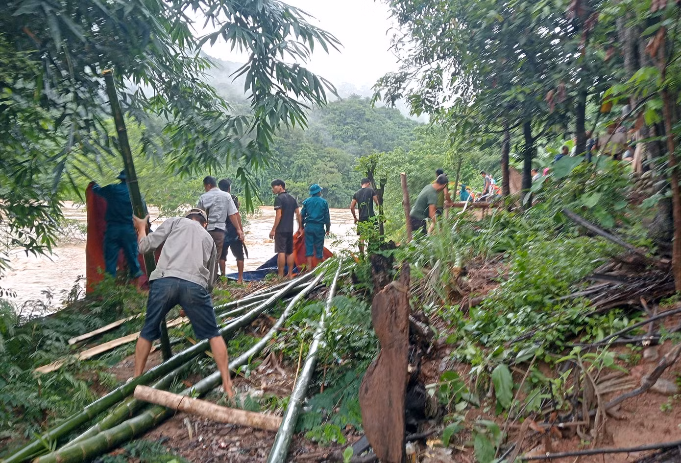 Người dân và cơ quan chức năng dùng bạt, bao tải cát, cọc tre gia cố bờ sông bị sạt lở.