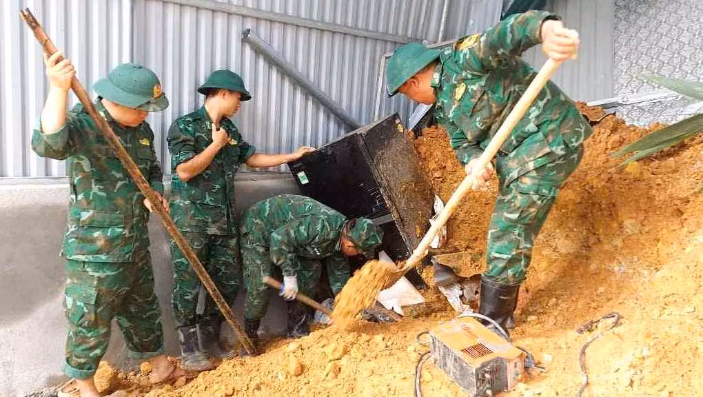 Các cán bộ chiến sĩ Đồn Biên phòng Na Loi tiến hành xúc đất để tìm kiếm các tài sản bị vùi lấp bên dưới.