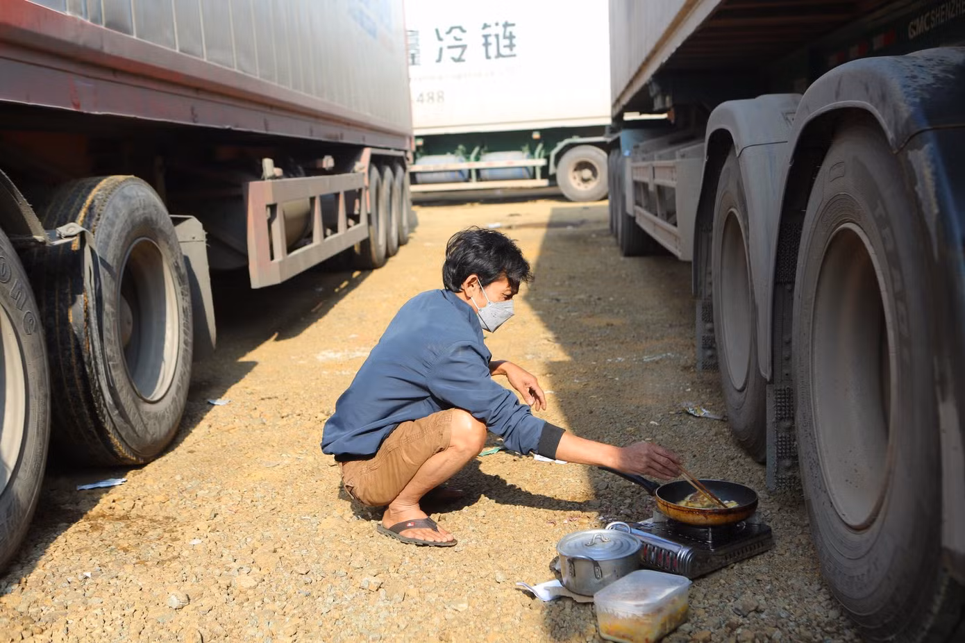 Cảnh nấu nướng tạm bợ xen lẫn nguy hiểm đến cháy nổ nhưng các lái xe không dám đi xa vì sợ mất hàng, tài sản -Ảnh: Duy Chiến