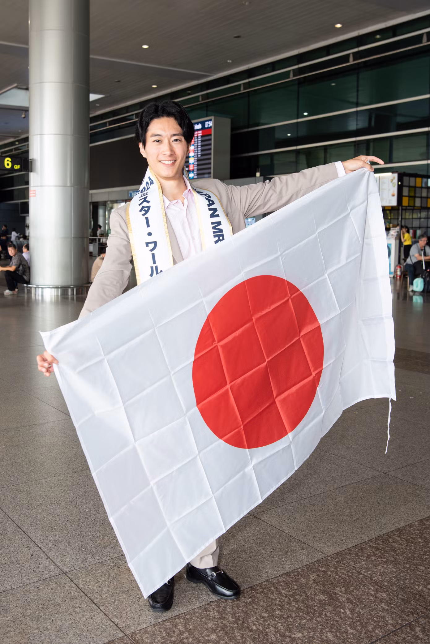 Mr World Japan đáp chuyến bay sớm đến Việt Nam sáng 5/11. Đại diện đến từ Nhật Bản chụp ảnh với quốc kỳ tại sân bay trước khi nhập cuộc Nam vương Thế giới.