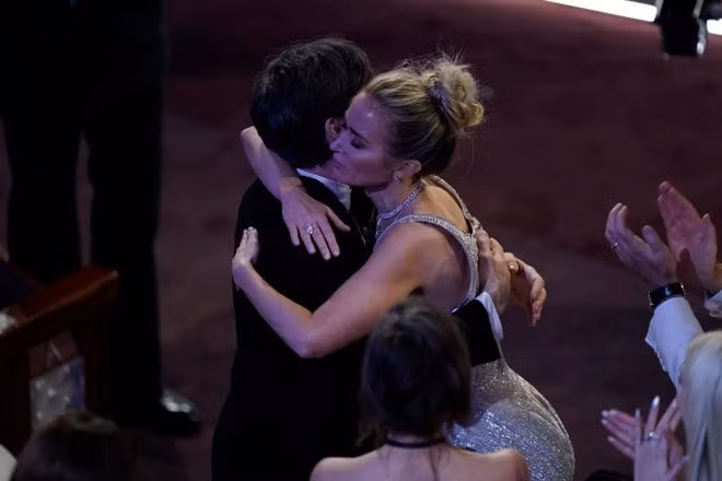 Cillian Murphy được báo chí quốc tế gọi vui là "tài tử lãi nhất Oscar 2024" khi nhận nhiều cái ôm, hôn từ đồng nghiệp. Trong ảnh, nam chính đóng vai cha đẻ bom nguyên tử được minh tinh Emily Blunt cổ vũ trước khi lên bục nhận tượng vàng danh giá.