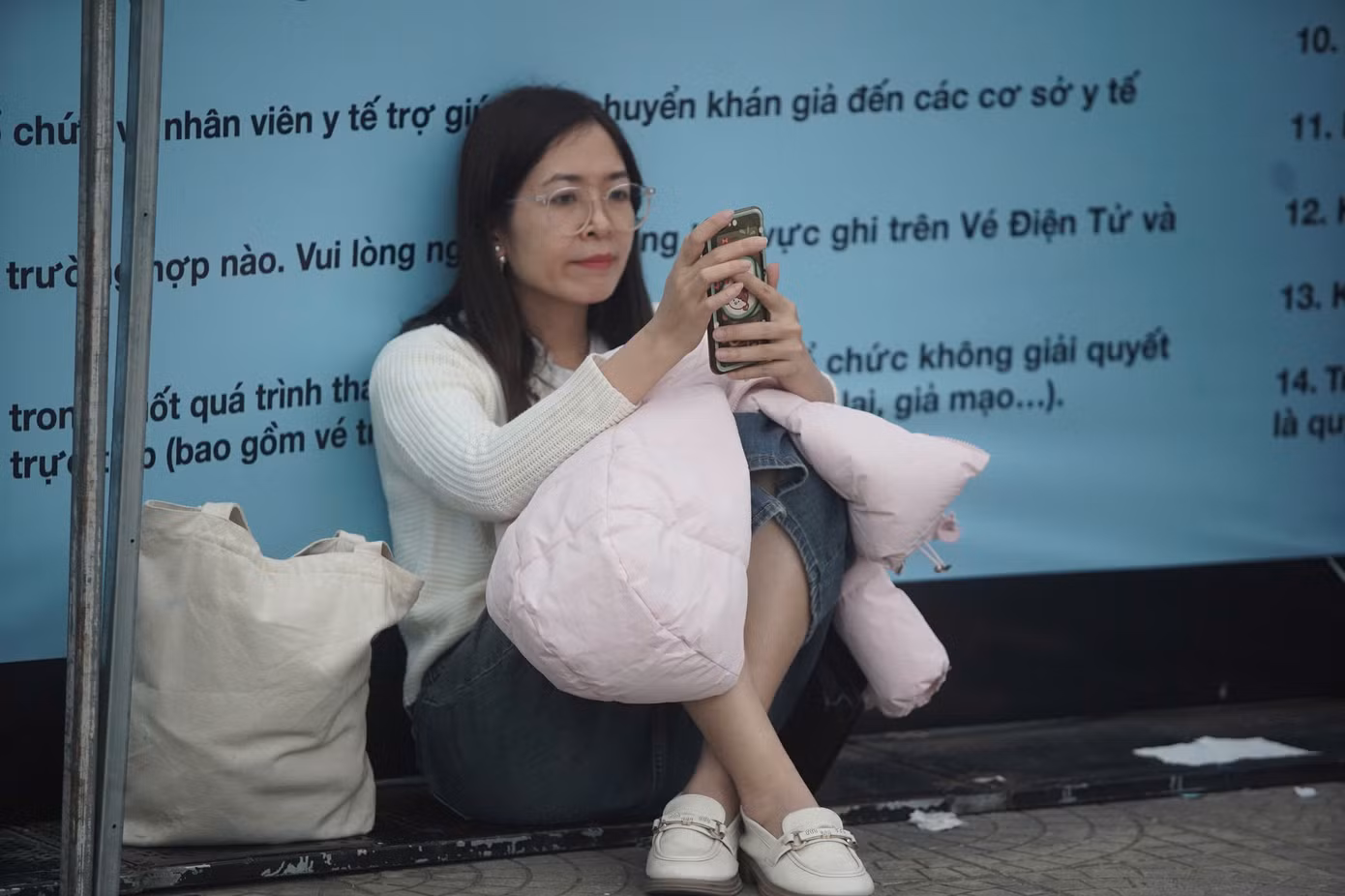 Loạt ảnh ghi lại cảnh giới trẻ ngồi quanh khu vực gần chỗ check-in. Khi được hỏi về việc nhiều người bất chấp cái lạnh của thời tiết Hà Nội, xếp hàng từ 5h sáng ở sân Mỹ Đình, Lan Hương (24 tuổi, Tuyên Quang) nói đó là quyền tự do của mỗi người. "Tôi mua vé ngồi nên không áp lực chuyện xếp hàng. Các bạn xếp hàng từ 5h sáng chủ yếu là mua vé đứng, đến sớm để giành chỗ đẹp", cô nói.