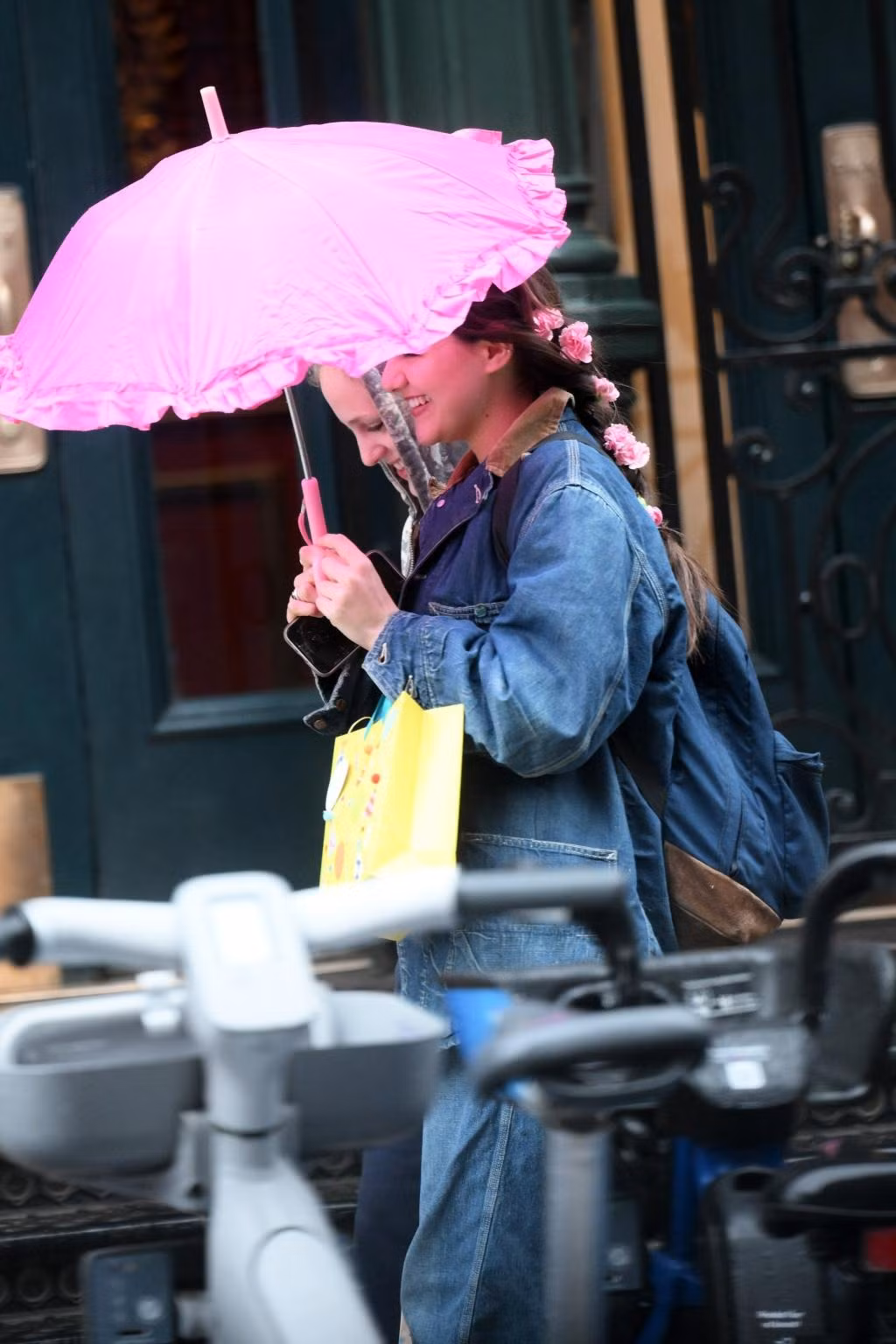 Khoảnh khắc Suri Cruise trò chuyện vui vẻ cùng bạn bè được paparazzi ghi lại. Ở tuổi 18, Suri theo đuổi phong cách nữ tính. Cô chọn tết tóc, cài hoa màu hồng trên đầu, ton-sur-ton với chiếc ô.