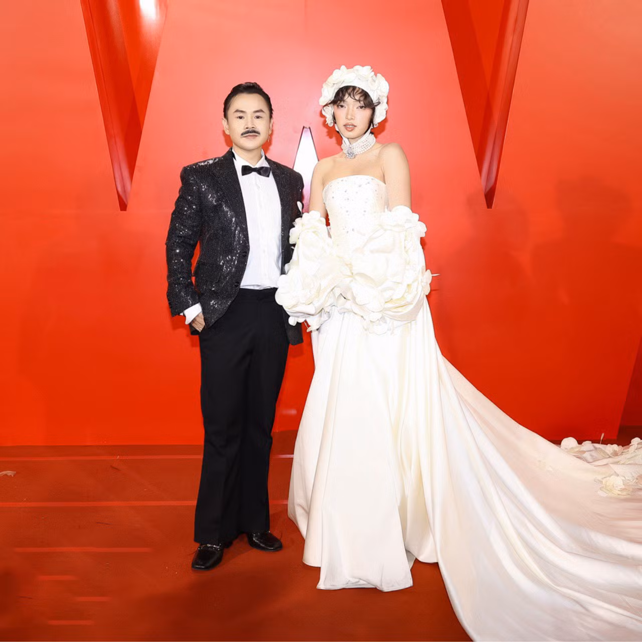 Binz sóng đôi cùng Châu Bùi tại thảm đỏ. Huấn luyện viên Rap Việt khác lạ khi để râu cùng phong cách chững chạc. Trong khi đó, Châu Bùi ghi điểm với thiết kế cúp ngực, phụ kiện đội đầu độc đáo.