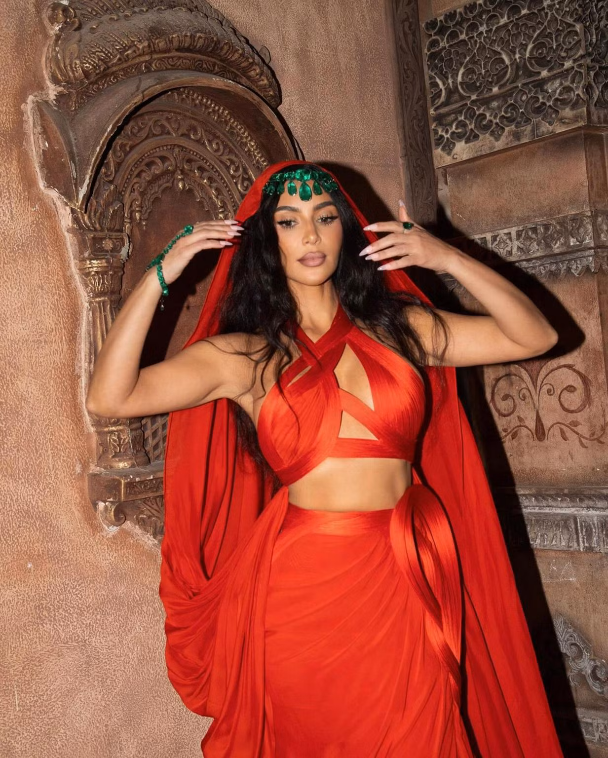 Tại lễ ban phước của "siêu đám cưới" nhà tỷ phú giàu nhất châu Á, Kim Kardashian thể hiện sự độc đáo khi chọn trang phục Gaurav Gupta Couture màu cam phối cùng những viên ngọc lục bảo Colombia cỡ lớn.