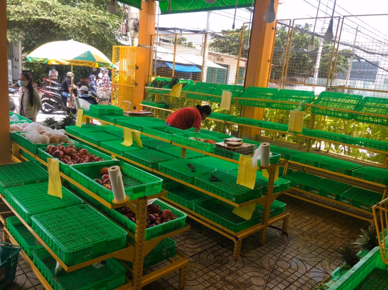 Cả quầy rau trái chỉ còn lại ít táo, lê. Nhân viên dọn dẹp và cho biết hết hàng rau cho buổi chiều
