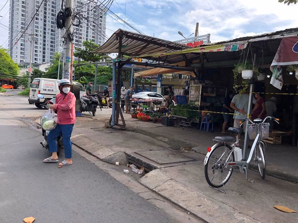 Một điểm bán rau tự phát chăng dây để giữ khoảng cách, nhưng người mua đều "chui dây" vào bên trong lựa hàng thoải mái.