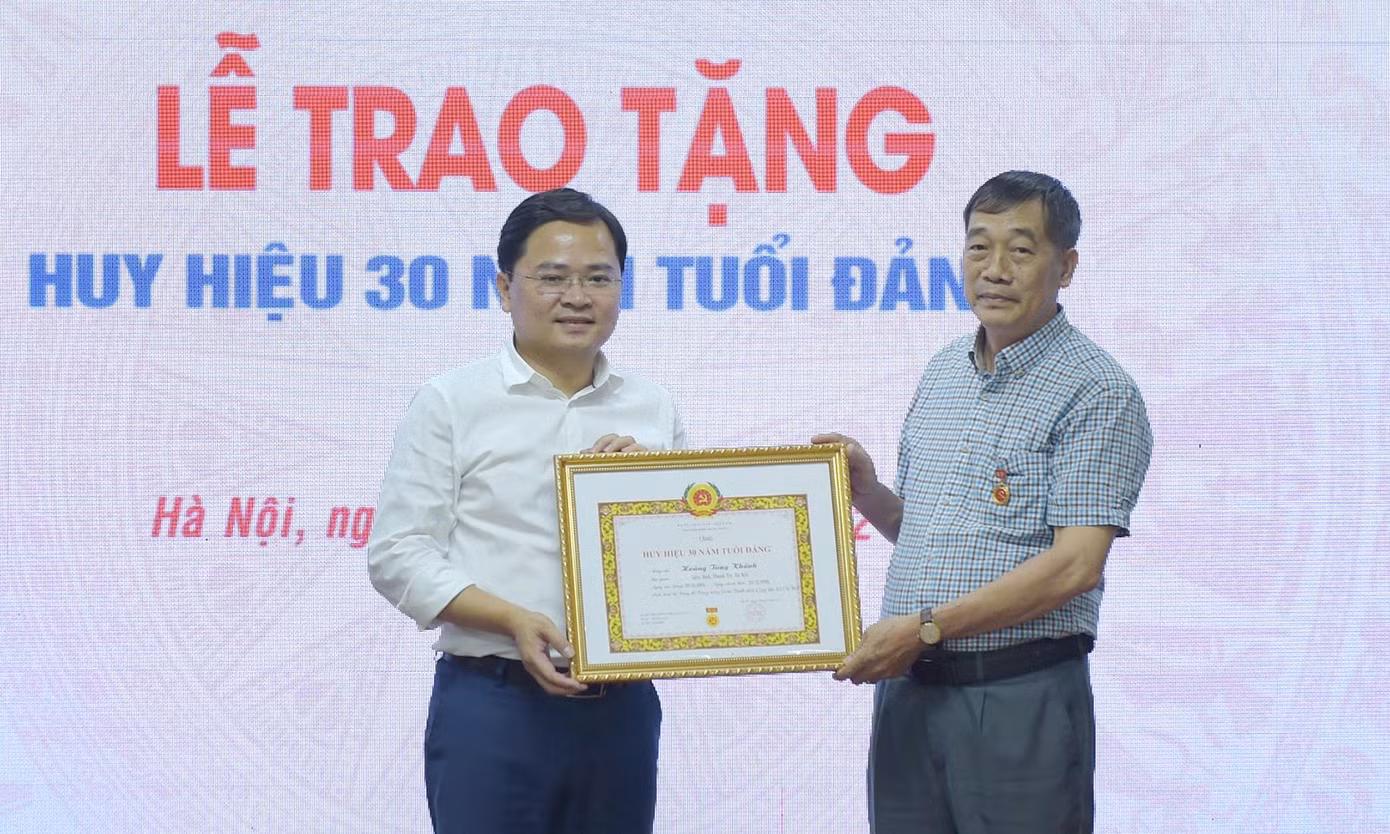 Anh Nguyễn Anh Tuấn trao huy hiệu 30 năm tuổi Đảng tặng ông Hoàng Tùng Khánh. Ảnh: Xuân Tùng
