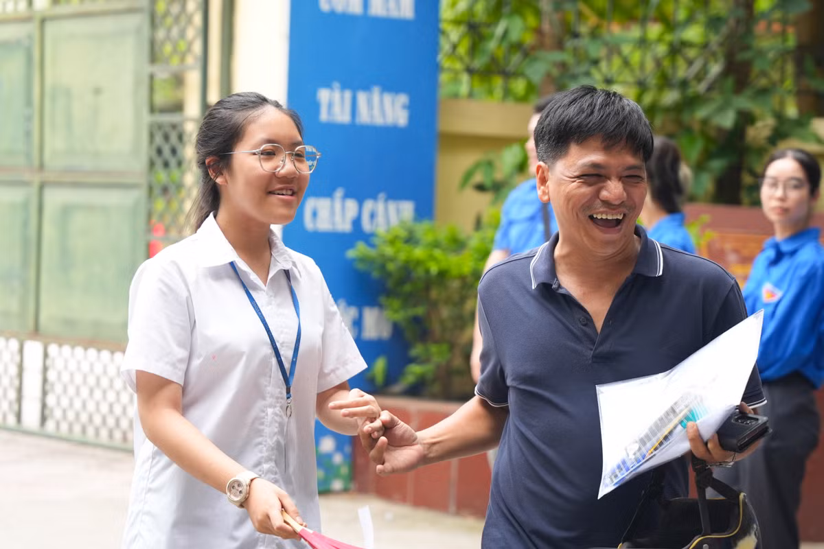 Người bố vui mừng nắm tay con khi nghe con gái thông báo làm bài thi tốt.