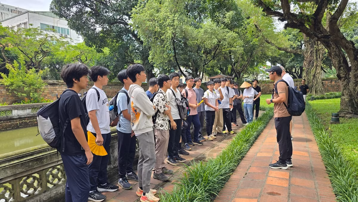 Một lớp học sinh trường quốc tế đang được hướng dẫn viên giới thiệu về Văn Miếu Quốc Tử Giám.