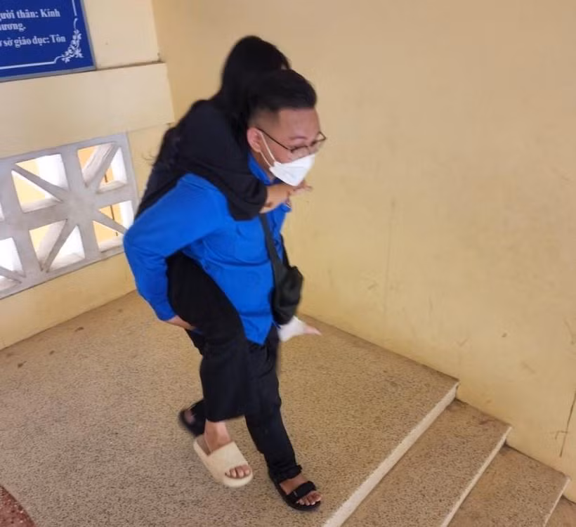 Đội viên Đội Tiếp sức mùa thi cõng thí sinh Nhi vào phòng thi. Ảnh: Đ.Đức.