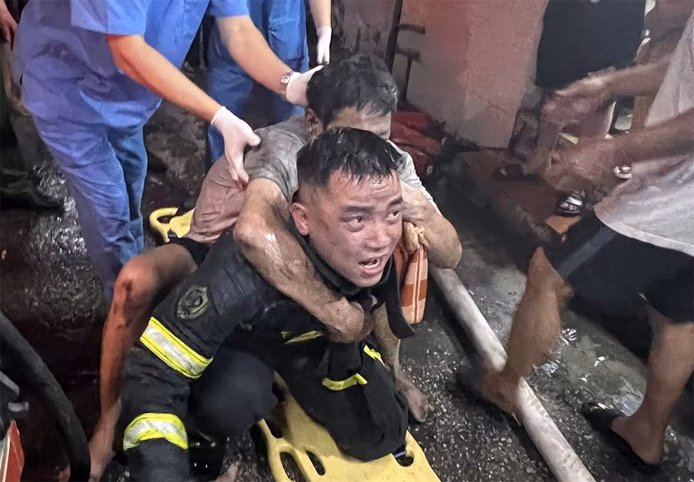 Thượng úy Nguyễn Viết Quân cõng nạn nhân mắc kẹt trong vụ cháy nhà xuống dưới. Ảnh: NVCC