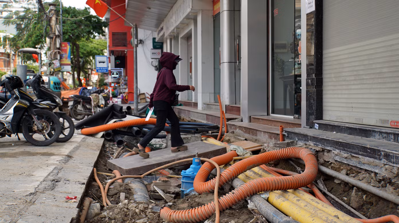 Các hộ dân, hộ kinh doanh đặt ván gỗ hoặc các vật liệu bắc cầu từ lòng đường vào nhà, phía dưới là hệ thống đường điện, cáp viễn thông, cống thoát nước...