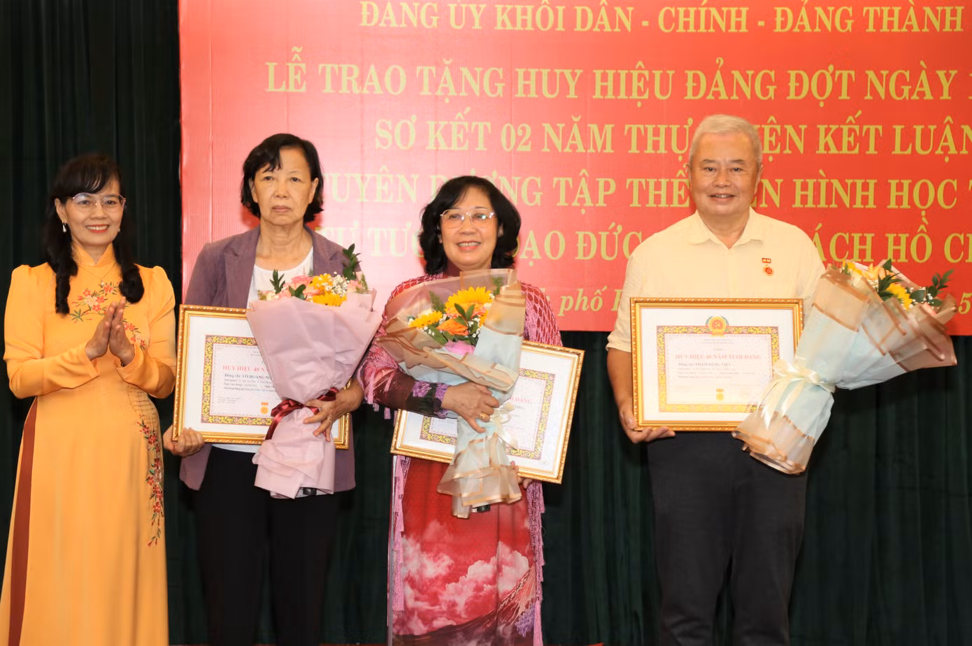 Phó Bí thư Thường trực Đảng ủy Khối Dân - Chính - Đảng TPHCM Nguyễn Thị Kim Dung (bìa trái) trao Huy hiệu Đảng cho đảng viên Nguyễn Thị Thanh Phương và Phạm Hùng Việt (thứ 3 và thứ 4 từ trái qua).