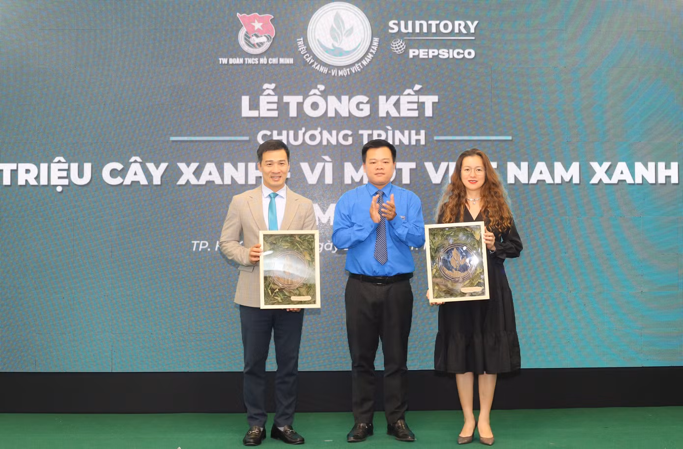 Phó Chánh Văn phòng Trung ương Đoàn Nguyễn Hải Nam (giữa) trao bức tranh “Kết nối màu xanh” đến các đơn vị đồng hành chương trình “Triệu cây xanh – Vì một Việt Nam xanh”. Tác phẩm được thực hiện bằng cách thu thập và lưu giữ những cành cây sau mỗi lần cắt tỉa định kỳ tại các điểm trồng cây trong hành trình vừa qua.