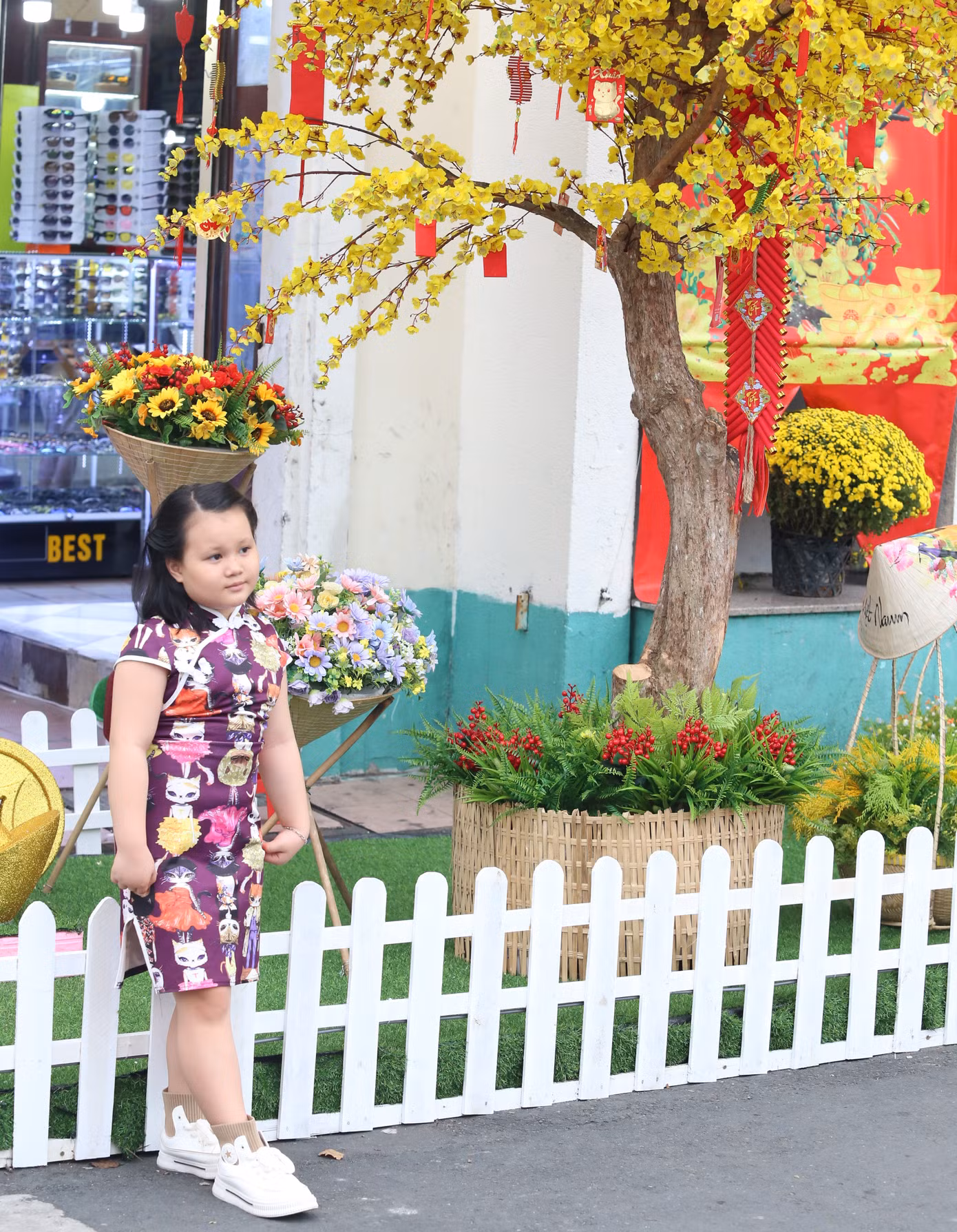 Em bé được người thân chụp ảnh với tiểu cảnh xuân trước chợ Bến Thành.