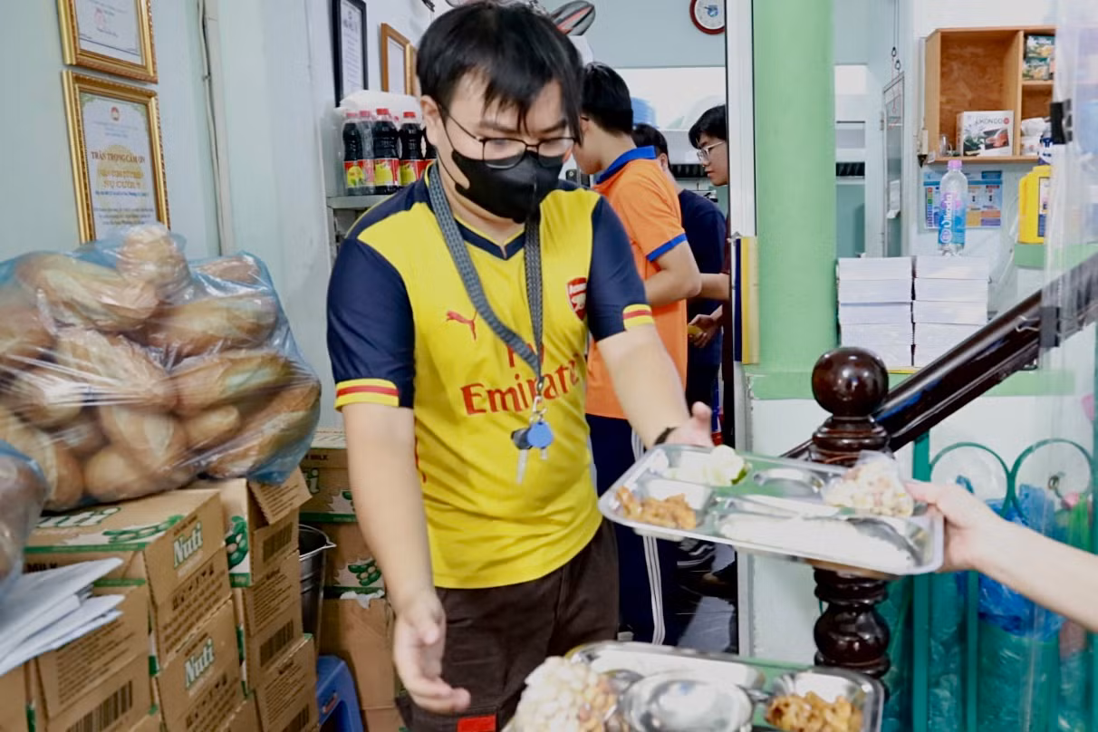 Anh Trương Huỳnh Trung Kiên phụ giúp quán chuyền cơm từ phòng bếp ra bàn ăn. (Ảnh: Thùy Trân)