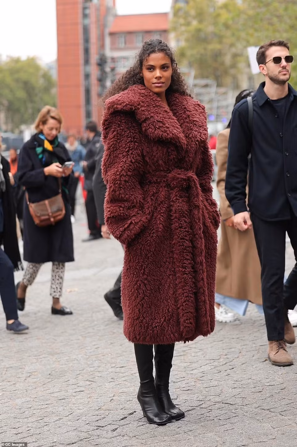 Nữ diễn viên Tina Kunakey khoác lên mình chiếc áo khoác đỏ tía xù xì.