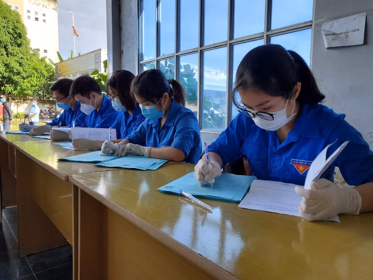 Lực lượng Đoàn viên thanh niên hỗ trợ ghi thông tin vào phiếu tiêm chủng cho người dân - Ảnh: Kim Hà.