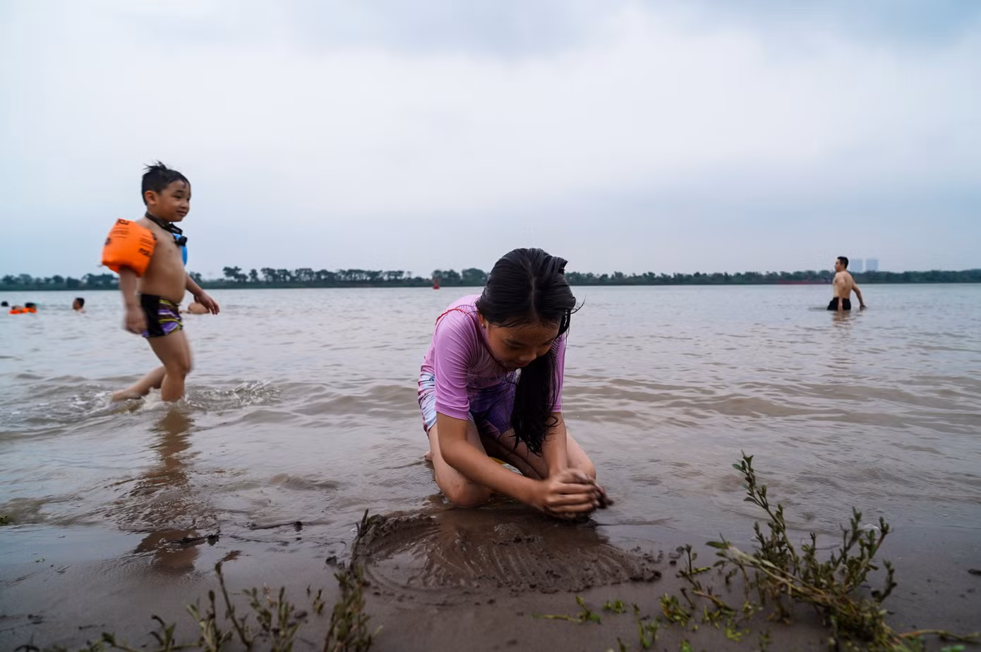 Ven bờ, nhiều em nhỏ thích thú nghịch cát, vui chơi dưới sự giám sát của người lớn.