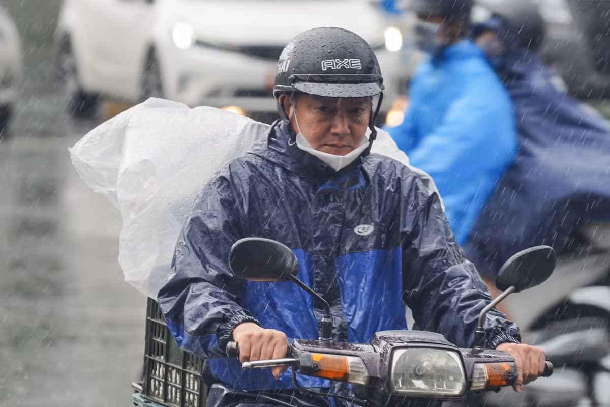Cơn mưa sáng sớm khiến người lao động càng thêm vất vả khi di chuyển.
