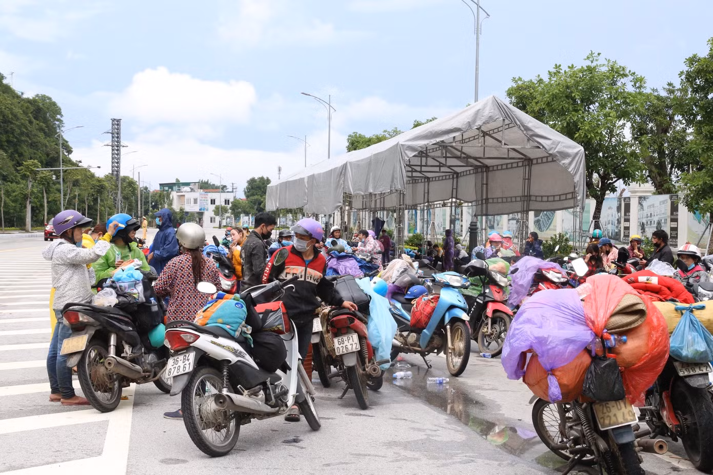 Ngày 5/10, nhiều người đi xe máy, chở người thân và hành lý nối đuôi nhau chạy qua chốt kiểm soát cầu Bến Thủy (Nghệ An). Sau khi khai báo y tế, người dân đứng bên lề đường chờ cảnh sát giao thông bố trí xe dẫn đường.